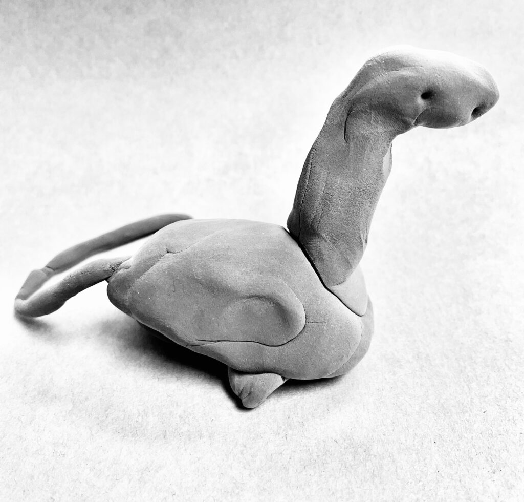 A black and white image of a clay dinosaur with a long neck