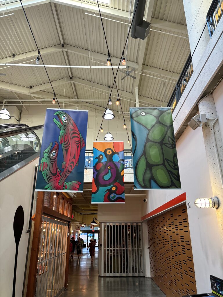 Three multicoloured banners in coast sailish and woodlands style hang from the rafters of River Market
