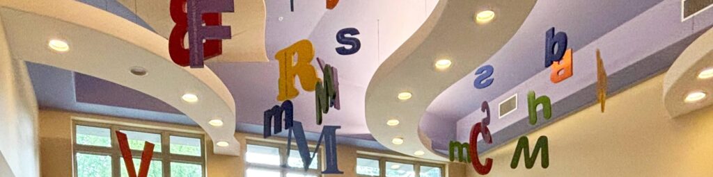 colourful letters hang from a light purple ceiling with wavy lights.