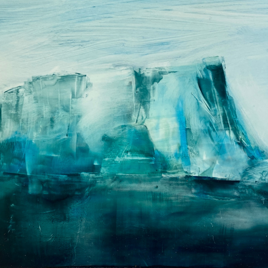 A deep teal green iceburg stretches out of dark water and into a lighter sky.