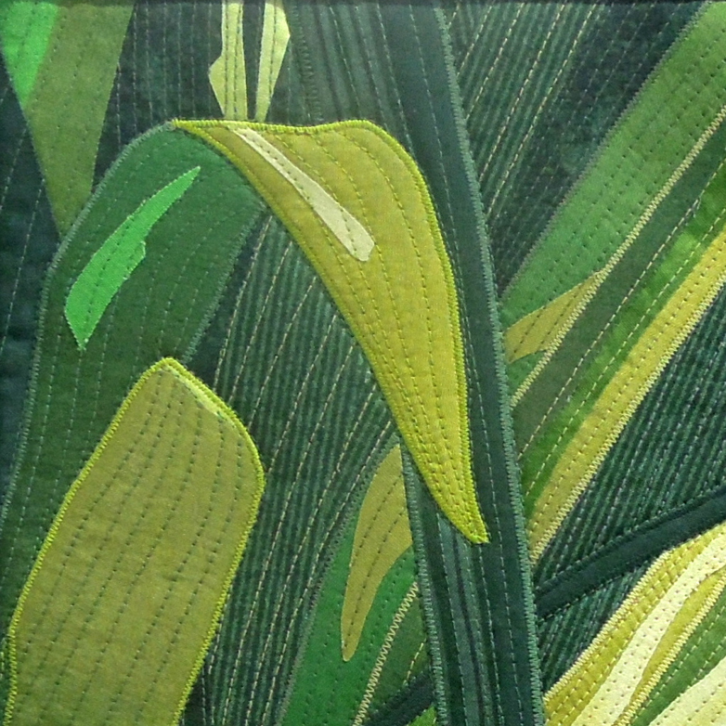 Quilted pieces of green fabric form tropical leaves.